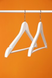 Photo of White clothes hangers on rack against orange background