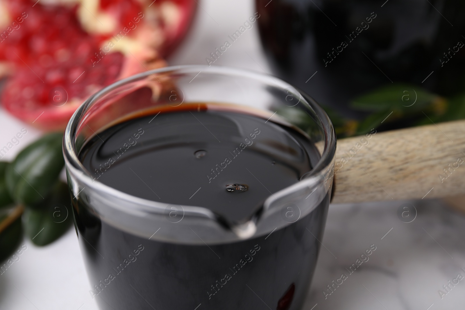 Photo of Tasty pomegranate sauce on white table, closeup