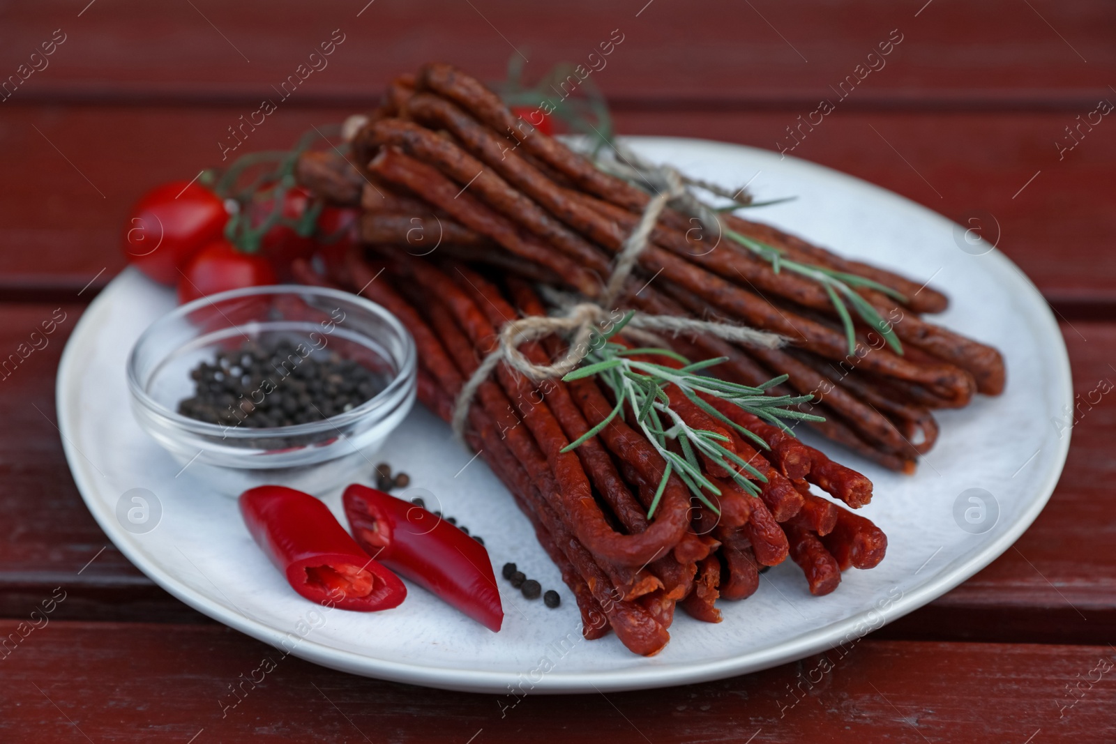 Photo of Tasty dry cured sausages (kabanosy) and ingredients on wooden table