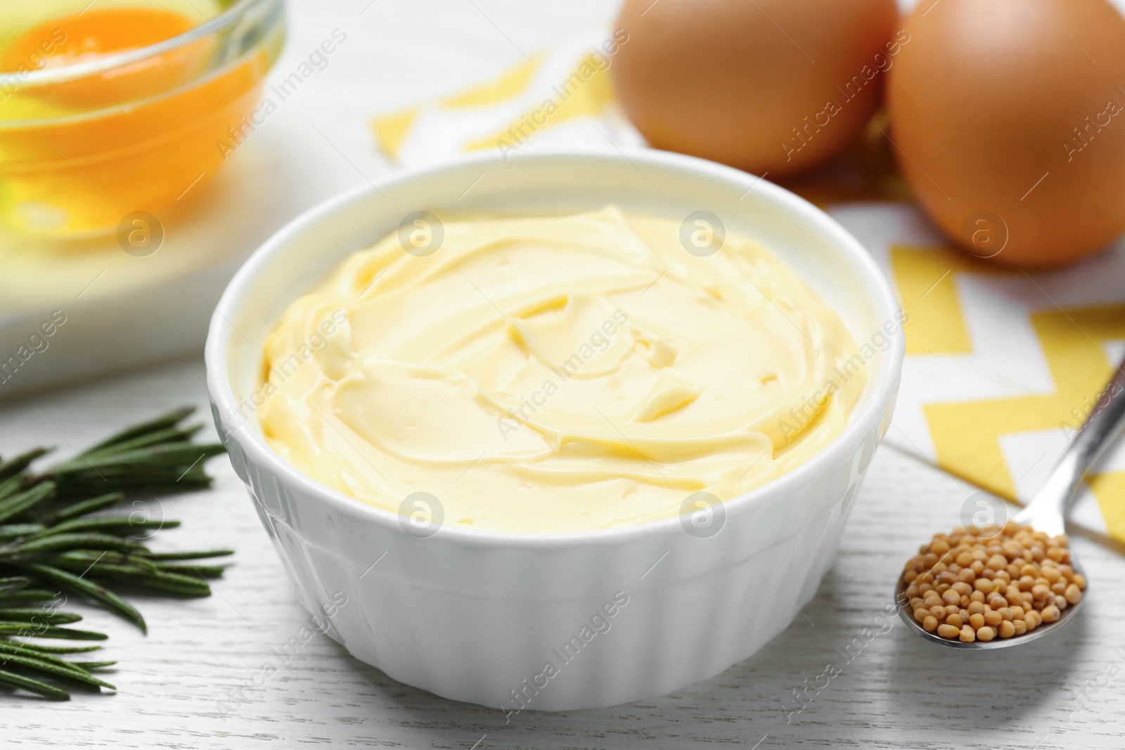 Photo of Delicious homemade mayonnaise with ingredients on white wooden table, closeup