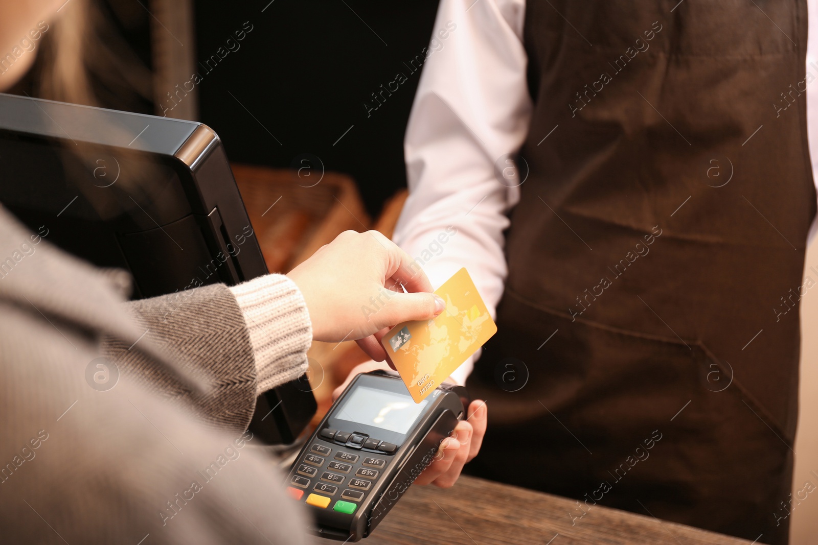 Photo of Woman with credit card using payment terminal at shop, closeup