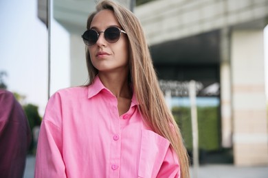 Photo of Beautiful young woman in stylish sunglasses on city street
