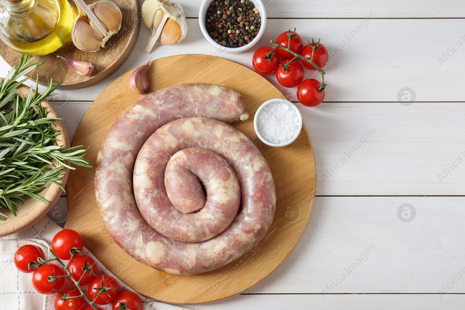 Photo of Raw homemade sausage, spices and other products on white wooden table, flat lay. Space for text