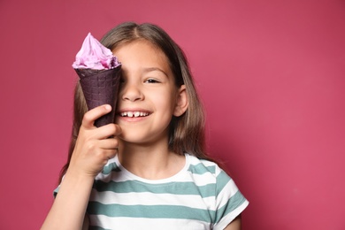 Adorable little girl with delicious ice cream against color background