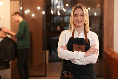 Portrait of professional hairdresser wearing apron in beauty salon, space for text