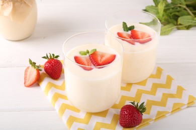 Photo of Tasty yogurt and strawberries in glasses on white wooden table, closeup