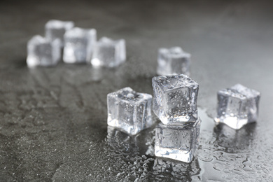 Crystal clear ice cubes on grey stone table. Space for text
