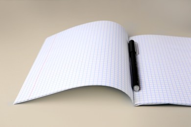 Photo of Copybook with erasable pen on beige background, closeup