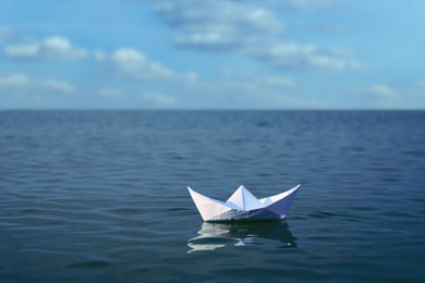 Image of White paper boat floating on calm sea 