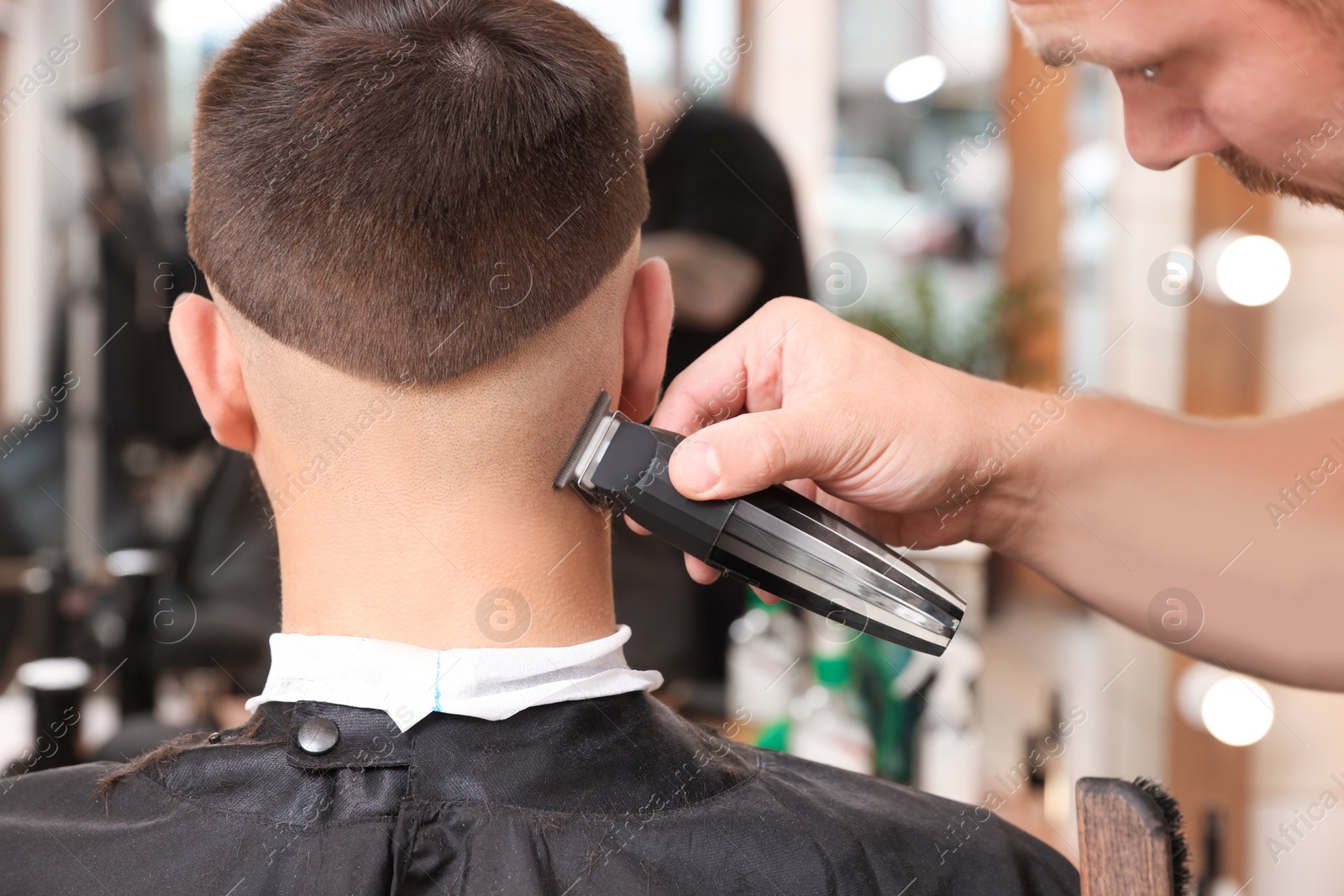 Photo of Professional hairdresser working with client in barbershop, closeup