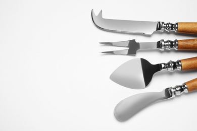 Cheese knives and fork on white background, top view