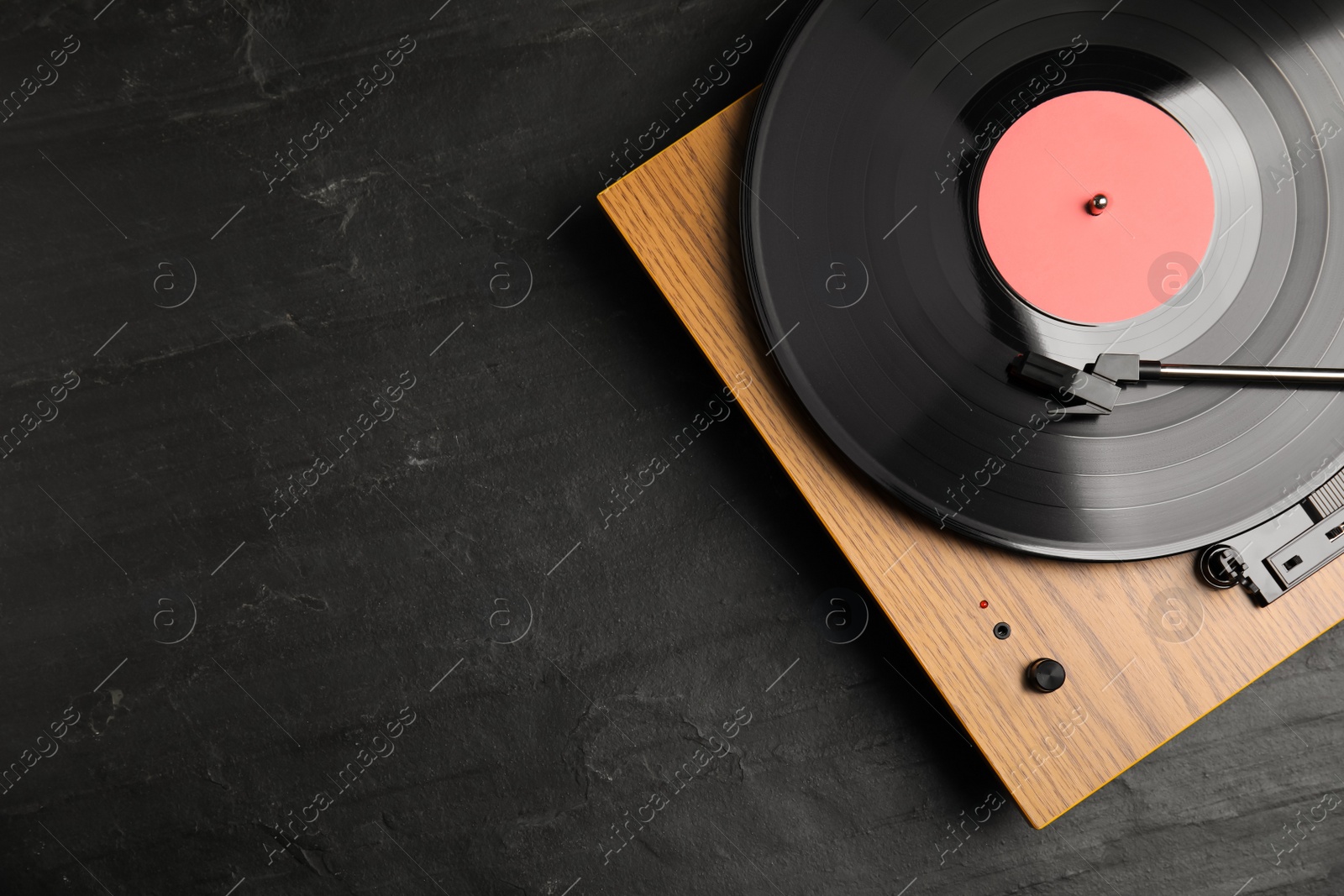 Photo of Turntable with vinyl record on black background, top view. Space for text