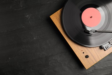 Photo of Turntable with vinyl record on black background, top view. Space for text