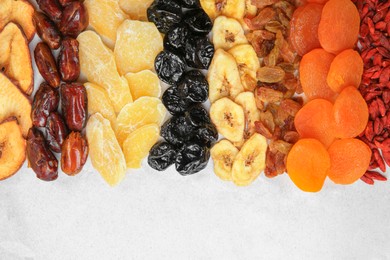 Different tasty dried fruits on paper, flat lay