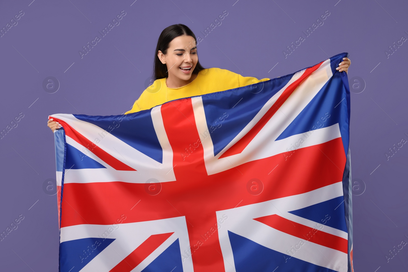 Photo of Happy young woman with flag of United Kingdom on violet background