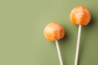 Tasty lollipops on green background, flat lay. Space for text