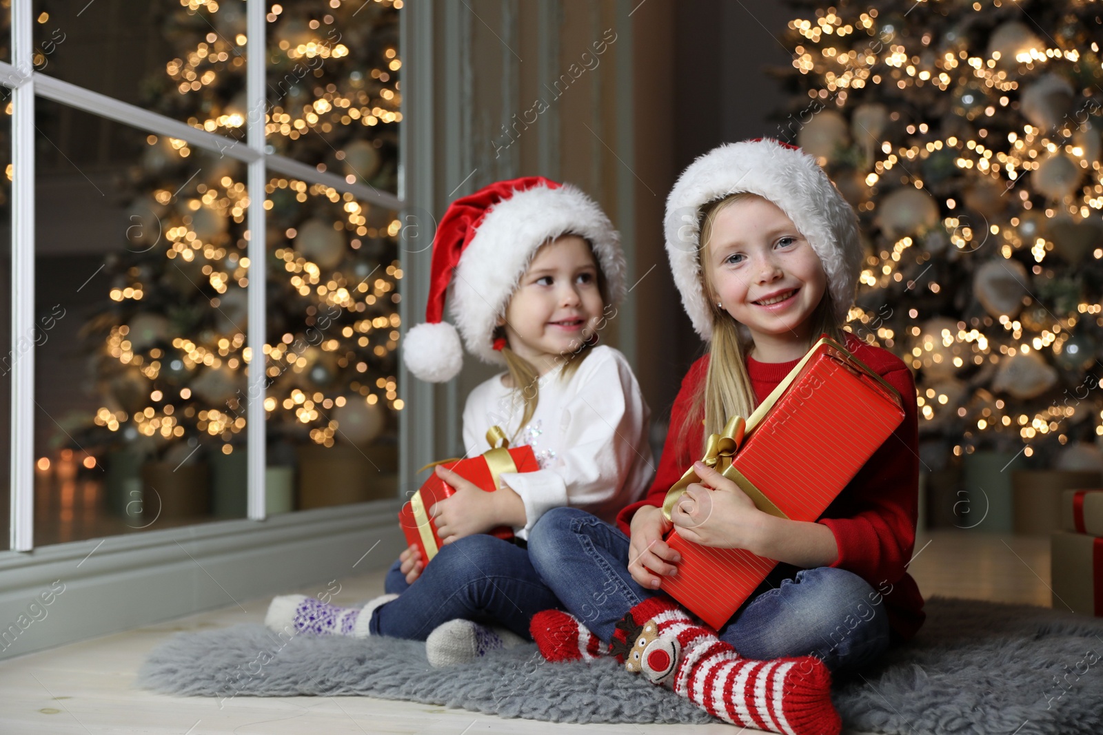 Photo of Cute little children with Christmas gifts at home