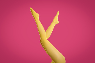 Photo of Woman wearing yellow tights on crimson background, closeup of legs