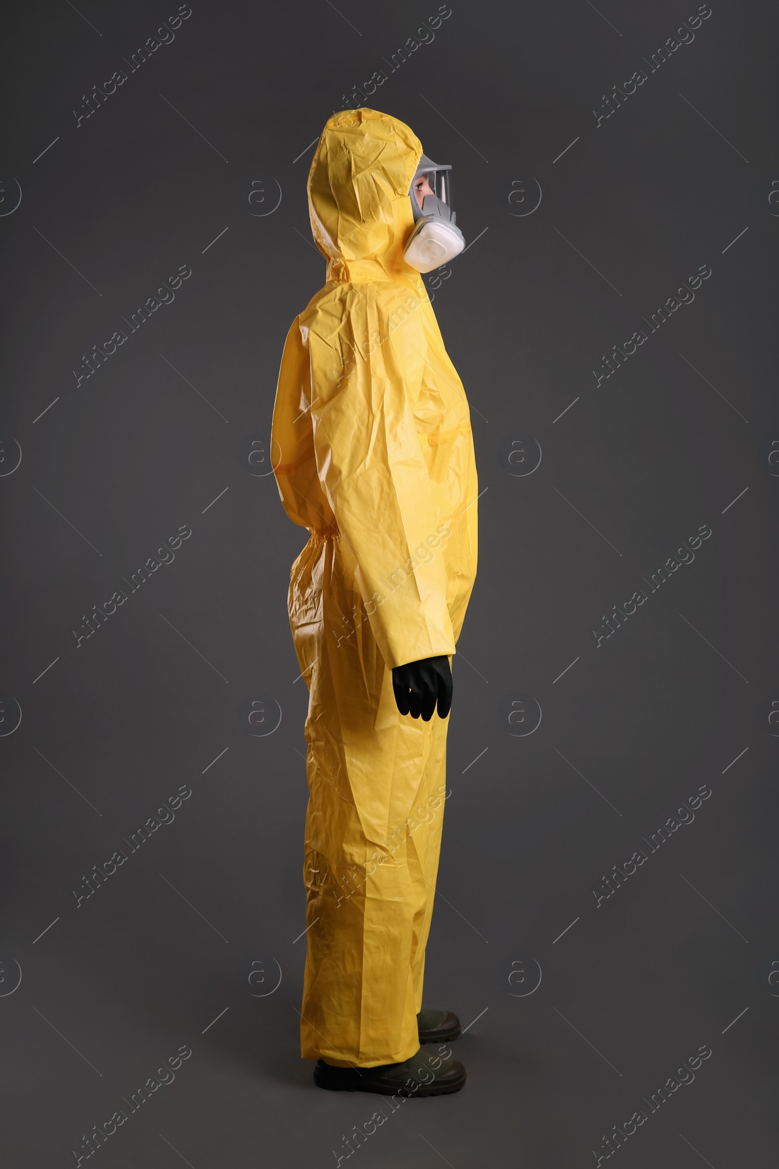 Photo of Woman wearing chemical protective suit on grey background. Virus research