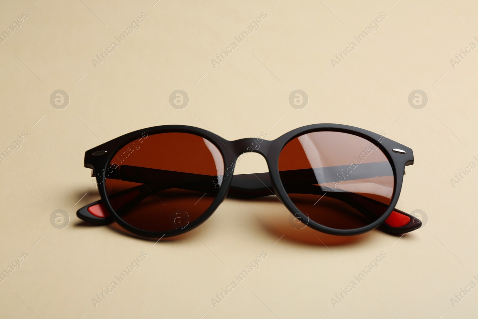 Photo of Stylish sunglasses on beige background. Fashionable accessory