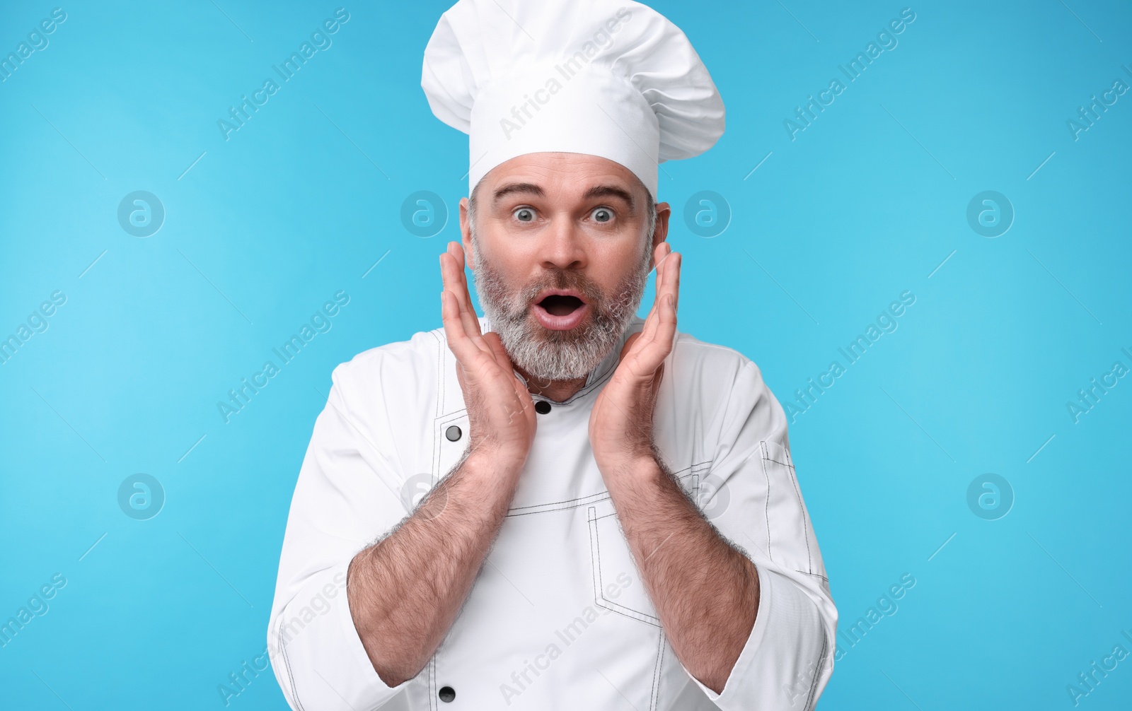 Photo of Surprised chef in uniform on light blue background
