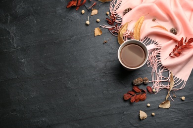 Flat lay composition with cup of hot drink and autumn leaves on black table, space for text. Cozy atmosphere