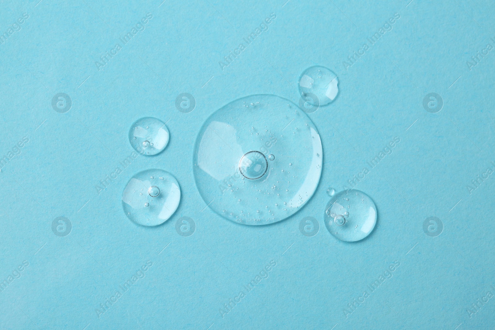 Photo of Samples of cosmetic serum on light blue background, flat lay