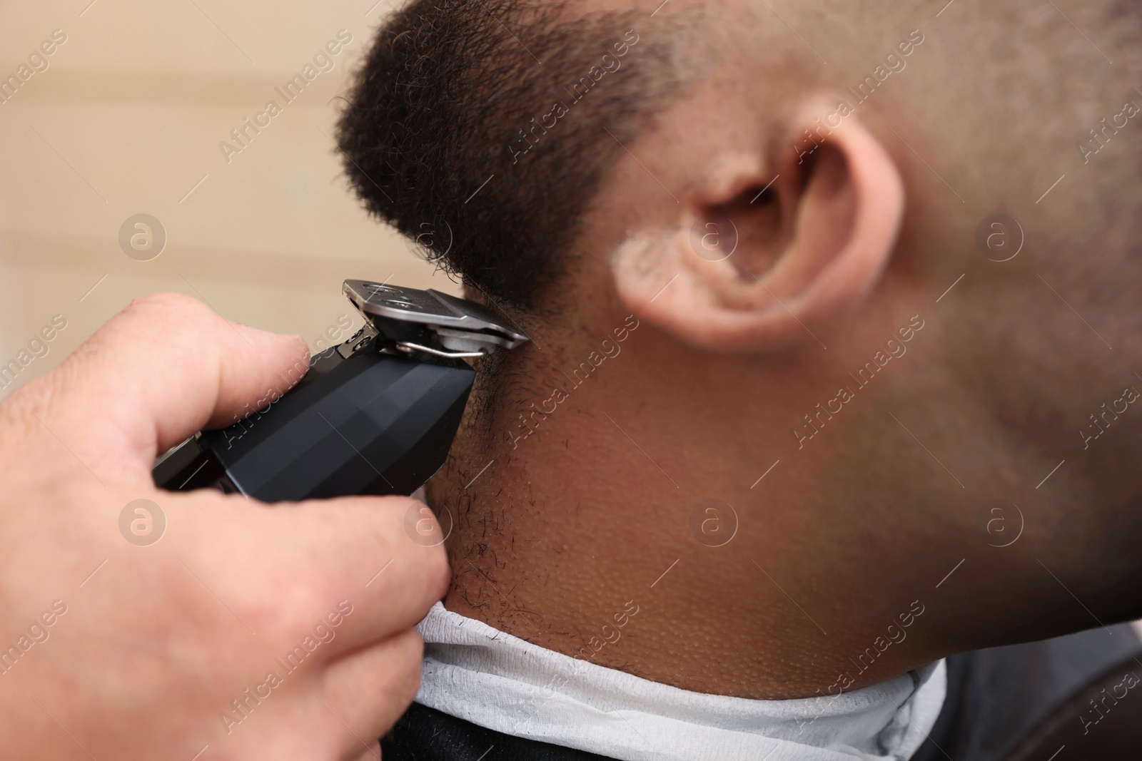 Photo of Professional hairdresser working with client in barbershop, closeup