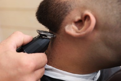 Photo of Professional hairdresser working with client in barbershop, closeup