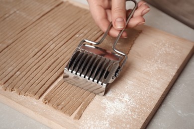 Woman making soba (buckwheat noodles) at light marble table, closeup