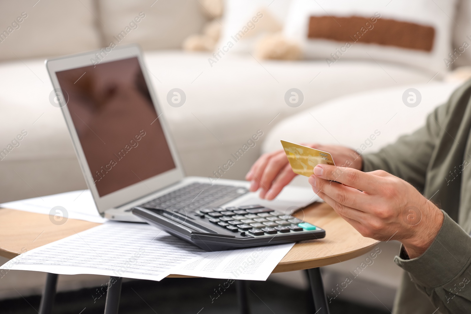 Photo of Man with laptop, calculator and credit card planning budget at table indoors, closeup. Debt problem