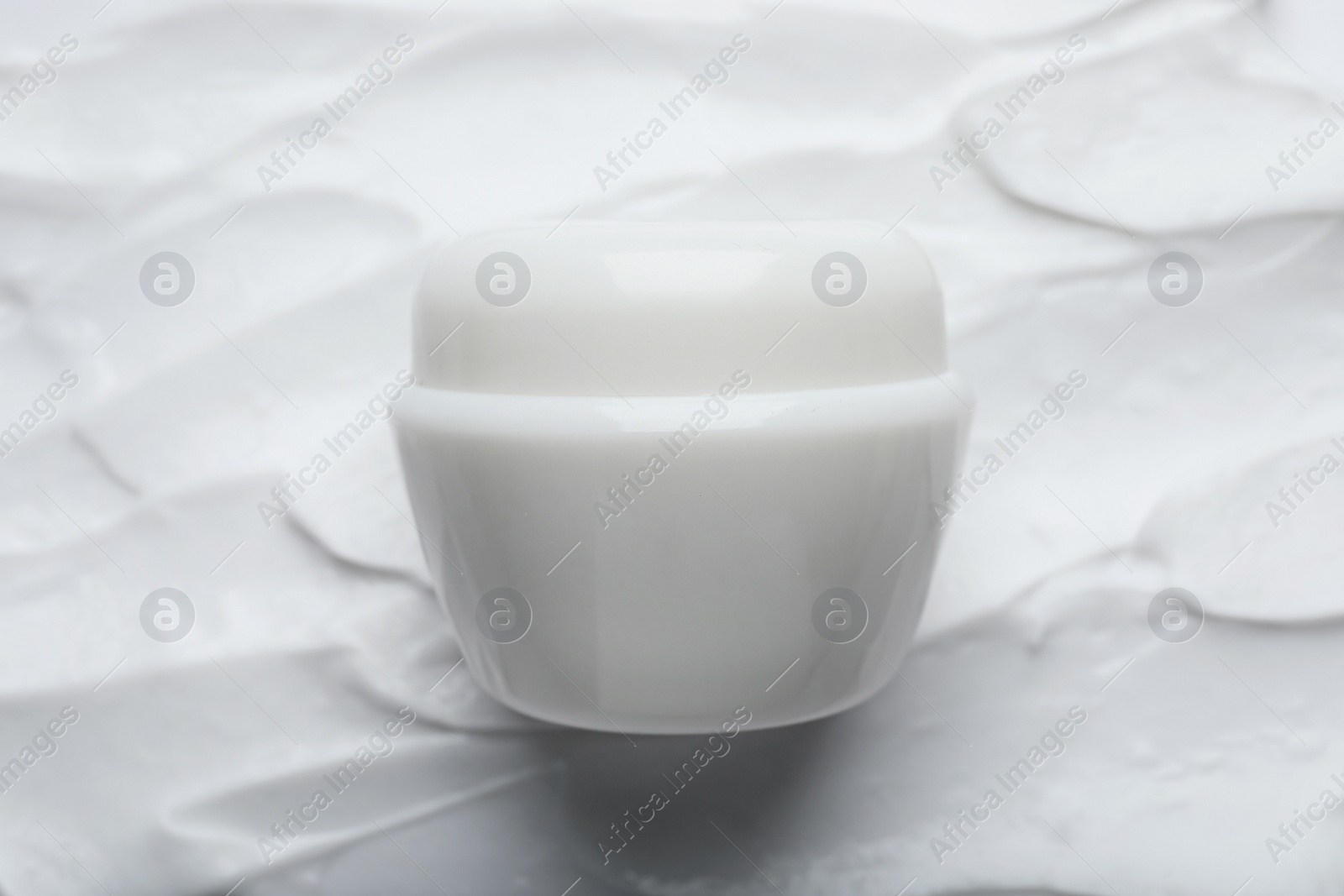 Photo of Jar on smeared white body cream, top view