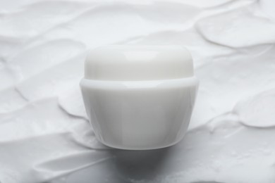 Photo of Jar on smeared white body cream, top view