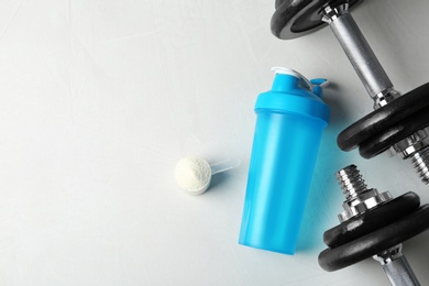 Photo of Flat lay composition with empty protein shake sport bottle and powder on table. Space for text