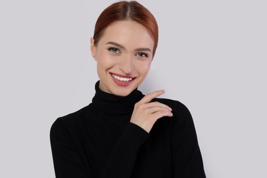 Portrait of beautiful young woman on light gray background