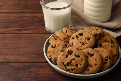 Delicious chocolate chip cookies and milk on wooden table. Space for text