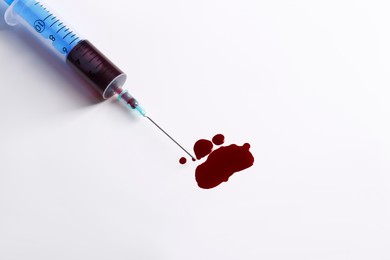 Plastic syringe with blood on white background