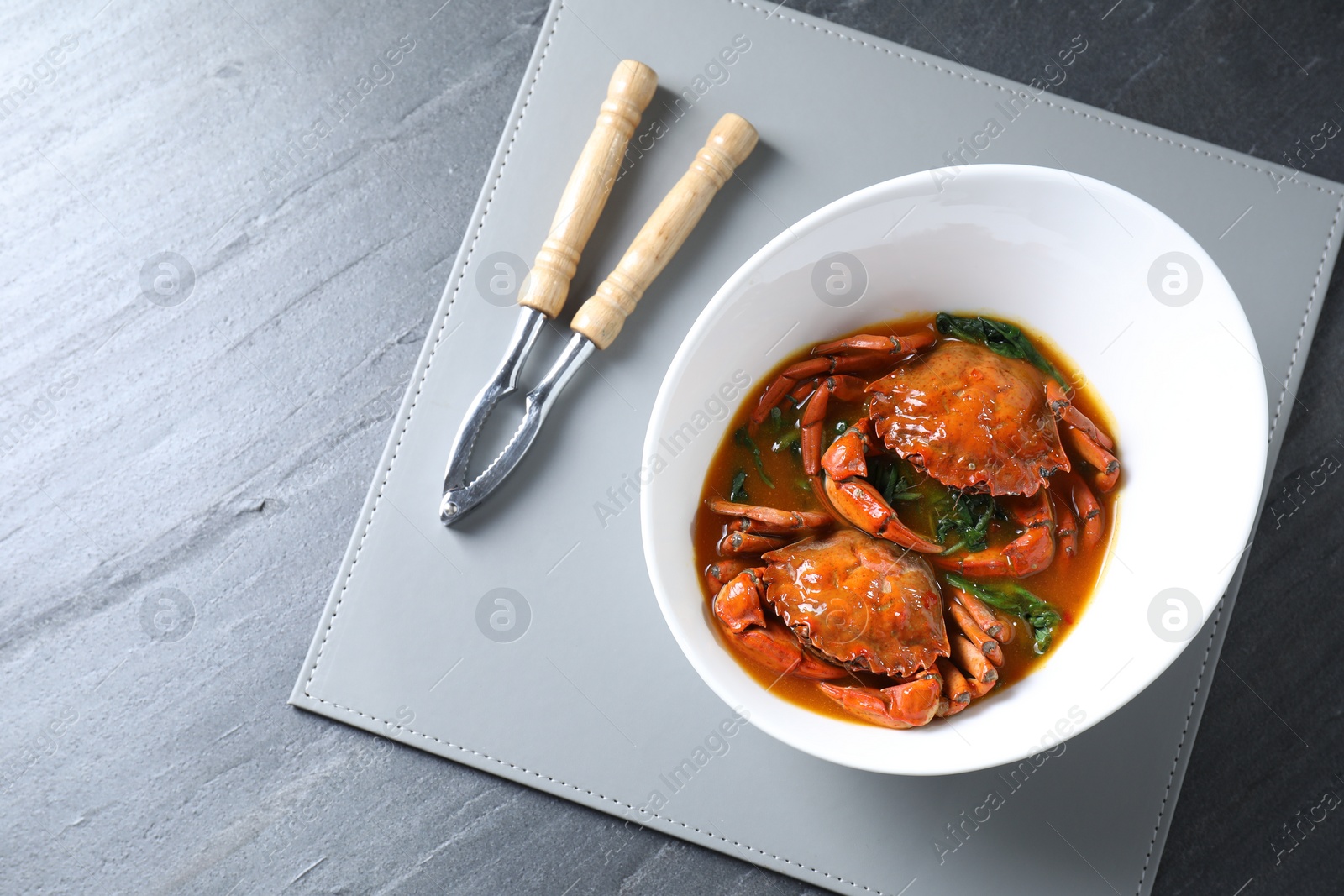 Photo of Delicious boiled crabs with sauce and cracker on grey table, top view