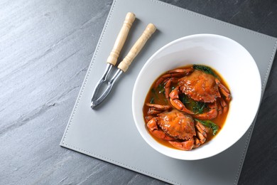 Photo of Delicious boiled crabs with sauce and cracker on grey table, top view