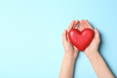 Photo of Woman holding heart on blue background, top view with space for text. Donation concept