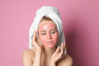 Young woman with pomegranate face mask on pink background