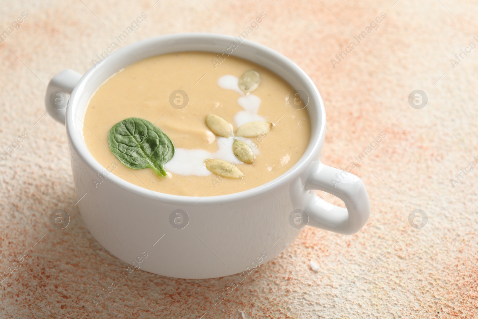 Photo of Healthy cream soup high in vegetable fats on color textured table, closeup