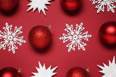 Photo of Christmas balls and decorative snowflakes on red background, flat lay