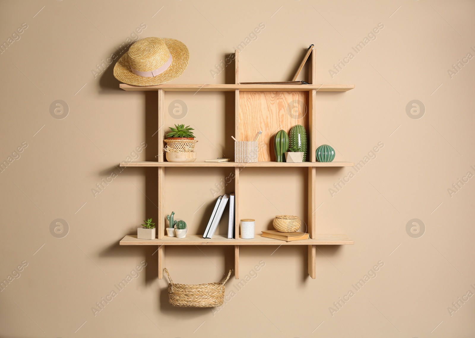 Photo of Wooden shelves with different decorative elements on beige wall