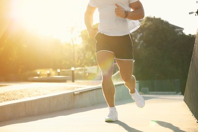 Man running outdoors on sunny day, closeup. Space for text