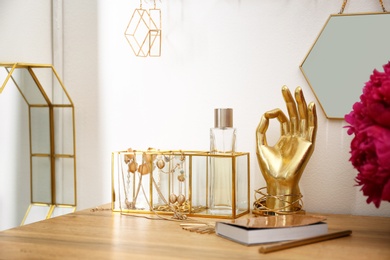 Composition with gold accessories and flowers on dressing table near white wall