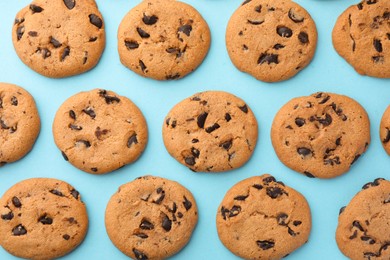Photo of Many delicious chocolate chip cookies on light blue background, flat lay