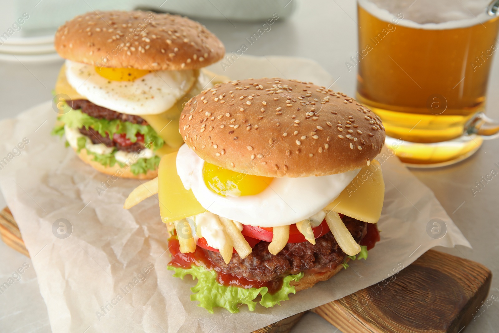 Photo of Tasty burgers with fried egg on wooden board