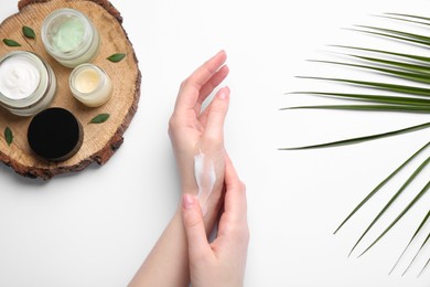 Woman applying hand cream on white background, top view