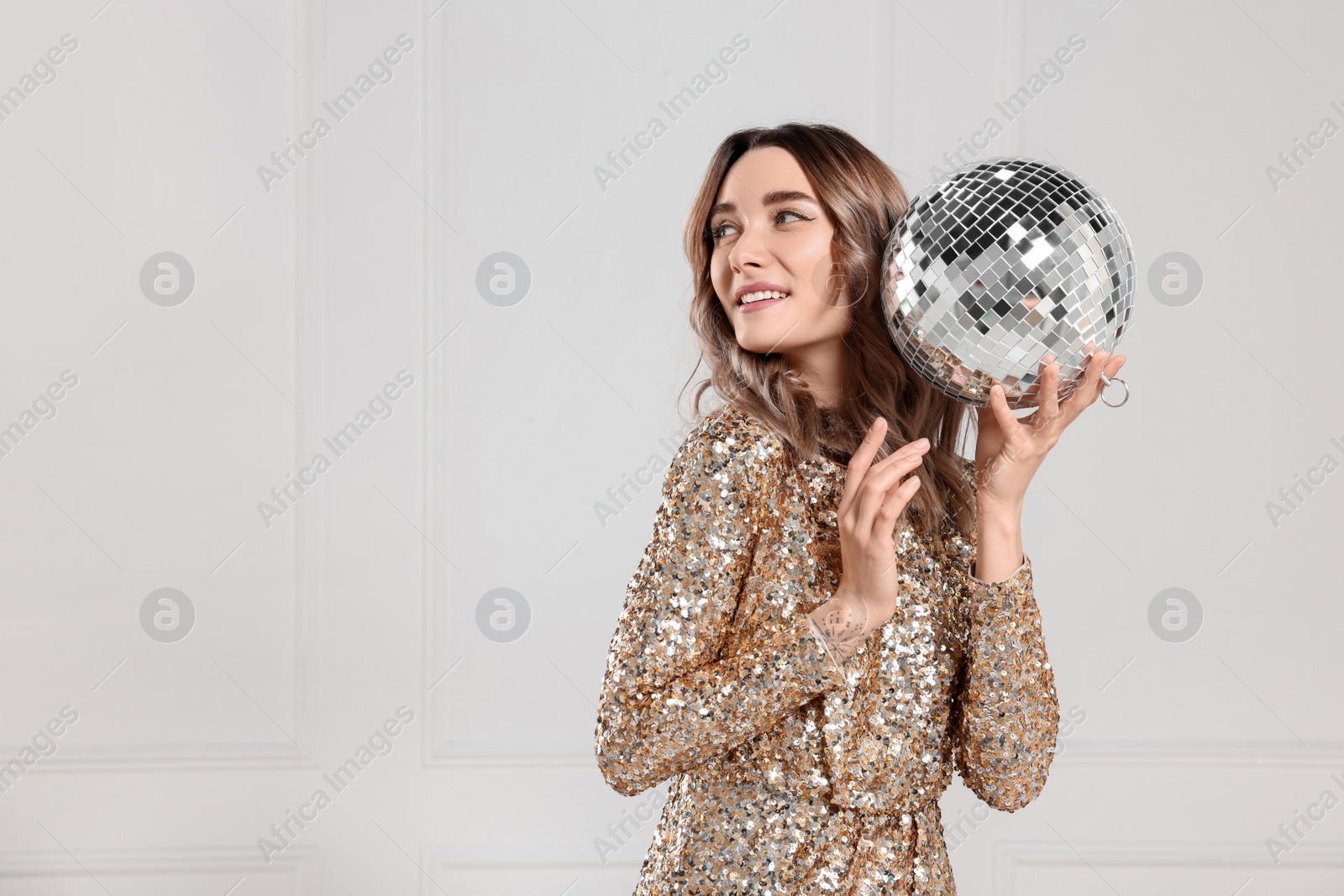 Photo of Beautiful woman in golden dress with disco ball posing on white background, space for text